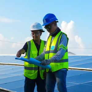 Solaren Renewable Energy Solutions team wearing branded safety helmets and reflective vests while installing solar panels on a commercial rooftop in the Philippines.