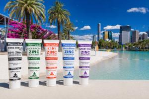 5 Tubes of sunscreen posed in front of South Bank public beach, Brisbane, Australia.