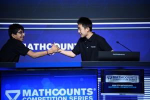 Two boys shake hands onstage.
