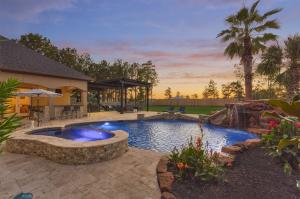 Picturesque image of luxury Montgomery, TX, home's outdoor living area including a pool and hot tub.