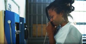 Woman making emotional phone call from prison; an official still image from the feature film FORTUITOUS premiering on VYRE Network beginning May 15, 2026
