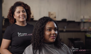 A Curl Academy-trained hair stylists prepares to cut her client's super curly hair.