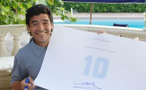 Maradona holding up one of his Hand-Signed Signature Sheets