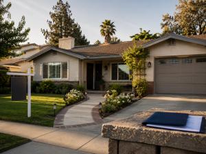 Exterior of a well-kept Southern California home with a blank yard sign, landscaped front walkway, and real estate documents in the foreground, illustrating reverse mortgage foreclosure issues facing heirs.