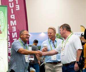 Image of 3 men smiling, two shaking hands and meeting for the first time on the show floor