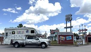 A truck with a decorated pick-up camper parked in front of the Route 66 Experience on the Illinois State Fairgrounds