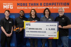 A group of students stands in front of a blue and orange Project MFG backdrop while holding a a ceremonial $5,000 check.