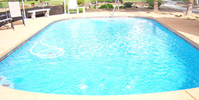 A clean oval-shaped swimming pool in a backyard setting, highlighting the everyday assets impacted by regional climate data and rising utility costs.