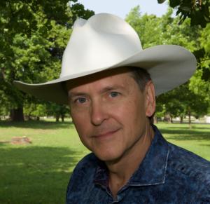 Gary Ty England in cowboy hat in timbered setting.