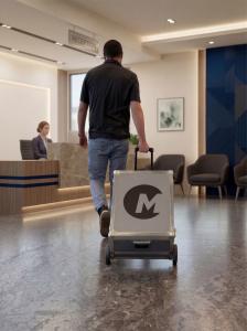 Man rolling a case with a portable TMS system into a clinic