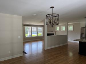 Interior painting and remodeling project by Marcos Painting in Nashua, New Hampshire, featuring an open-concept dining and living area with neutral warm beige walls, custom white columns, crown molding, and hardwood floor finishing in a residential home.