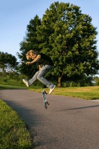 High school senior performing a skateboard trick on a paved path during an outdoor portrait session at sunset in Central Pennsylvania.