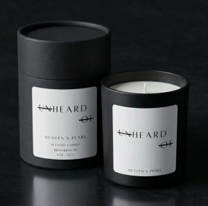 A luxury matte black UNHEARD OF candle next to its matching black cylinder packaging, labeled Heaven's Pearl.