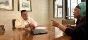 Marcelo Umanzor Blanco seated at a conference table with a laptop, engaged in a professional consultation with a female client.