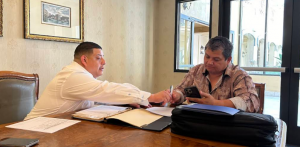 Marcelo Umanzor Blanco handing a pen to a client to sign business formation documents across a large wooden conference table.