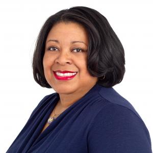 Professional headshot of Jenna Bryant, Senior Program Director at MDC and member of the 2026 Elizabeth Dole Fellowship Class, smiling and wearing a navy blue top against a light gray background.