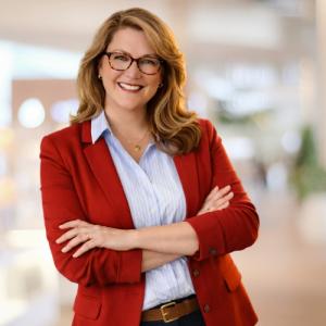 Melissa Fisher Managing Director of Peak Road Partners in red blazer with arms folder