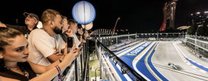 Spectators overlook the brightly lit Marina Bay Street Circuit from a luxury hospitality suite as a racing car speeds by during the night-time f1 singapore Grand Prix.