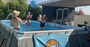 Family enjoying an above-ground Now Pools backyard pool in Phoenix with the Now Pools logo displayed on the pool.