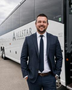 Jason Fritz, President & CEO of ALLSTAR Chauffeured Services, standing in front of a new 56-passenger MCI J4500 luxury motorcoach recently added to the company fleet.