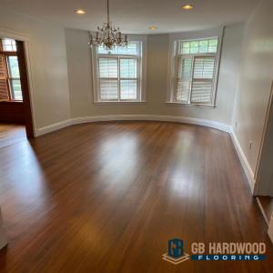 Refinished hardwood floors in a Greater Boston home by GB Hardwood Floor Inc, showing warm custom stain finish in a curved dining room with natural light.