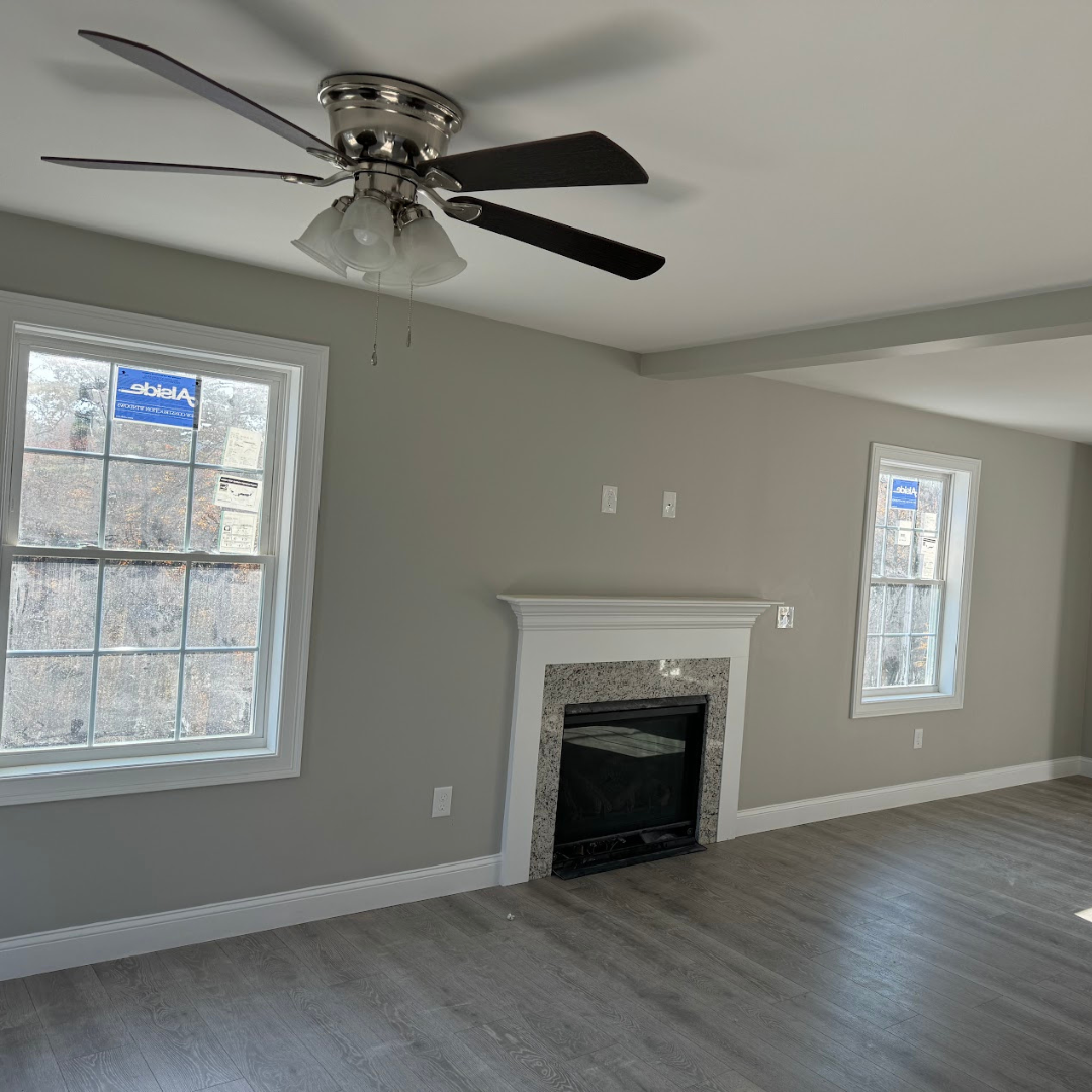 Freshly painted living room interior by Marco's Painting in Southern New Hampshire featuring neutral gray walls, white trim, fireplace detail and modern flooring.