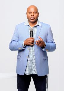 Kevin D. Williams, Dallas Communication Strategist and bestselling author of Unlocking Opportunities, speaking on stage with microphone in light blue blazer.