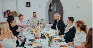 Guests seated at the CHECKMATE cultural salon installation in Sofia surrounded by candles, sculptural food, and contemporary art elements.