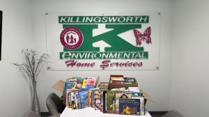 Books collected by team members on a table under the Killingsworth logo