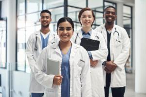 photo group of four health care professionals in white lab coats one standing out in front as the group leader