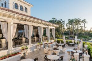 Outdoor dining area at The Club at Mediterra with tables overlooking a grand lawn and golf course views.