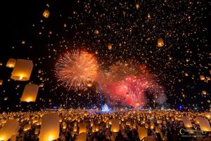 Thousands of glowing sky lanterns and colorful fireworks lighting up the night sky at the Chiang Mai CAD Yi Peng Lantern Festival.