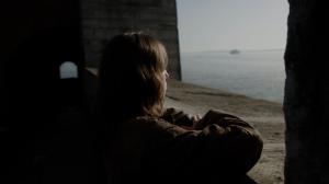 Image of young woman stood at wall looking out to sea