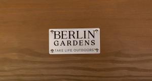 Close-up of a Berlin Gardens brand plaque mounted on a cedar pavilion at Millwest Amish Furniture in Plain City, Ohio.