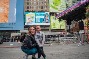Kimberly Spencer and her eight-year-old son Declan look up at an It’s Just a Fart billboard in Times Square during a family entrepreneurship and visibility campaign focused on storytelling, trust, and modern media.