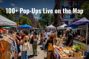 Busy outdoor urban pop-up market on a city street with vendors selling handmade empanadas, vintage clothing, and art to a diverse crowd, with the text "100+ Pop-Ups Live on the Map" overlaid.