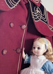 Alice in Wonderland doll admires buttons on child's vintage majorette jacket