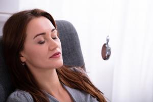 photo of a woman laying back in a chair with a Hypnotherapist inducing a trance with a stop watch
