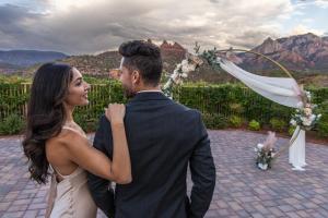 A couple looks at each other in front of a wedding arch and the red rock landscape of Sedona, Arizona.