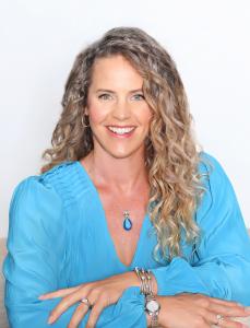 Kari Gras, smiling with turquoise dress and arms crossed in front