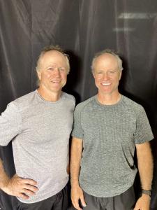 Twin brothers Jeff and Jess Graba standing side by side at Midwest Gymnastics in Little Canada, Minnesota.