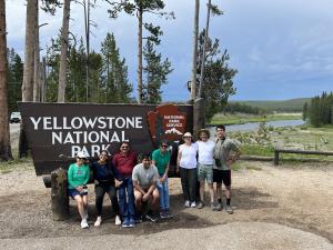 Multi-family group on private Teton Excursions tour at Yellowstone National Park entrance sign