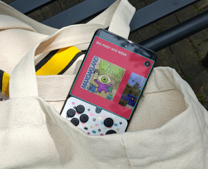 A Playtiles controller stick on a phone screen, inside a tote-bag.