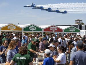 Volunteer teams support concession operations during a major U.S. air show as large crowds gather beneath aerial demonstrations, illustrating community fundraising partnerships connected to the Columbus Air Show Presented by ScottsMiracle-Gro.