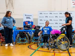 Three individuals pose with adaptive sports equipment