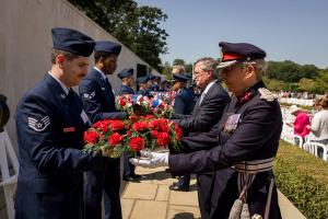 Wreath bearers from area U.S. Air Force bases pass more than 100 wreaths over to the presenters who laid them at the Walls of the Missing May 25, 2026, during the Memorial Day ceremony at Cambridge American Cemetery. (ABMC/Richard Howell)