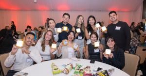 Corporate team members smiling and holding SolarBuddy solar lights during a Strayboots CSR team-building event.