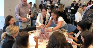 Corporate employees working together around a table during an indoor Strayboots tabletop team-building challenge.