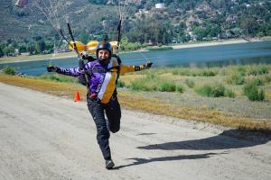 Female skydiver landing near a lake