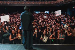 Anuv Jain stands on stage in front of a packed audience during his sold out Dastakhat World Tour 2026 concert at The Regency Ballroom in San Francisco, produced by Kash Patel Productions, as fans hold signs and capture the moment on their phones. Photo by